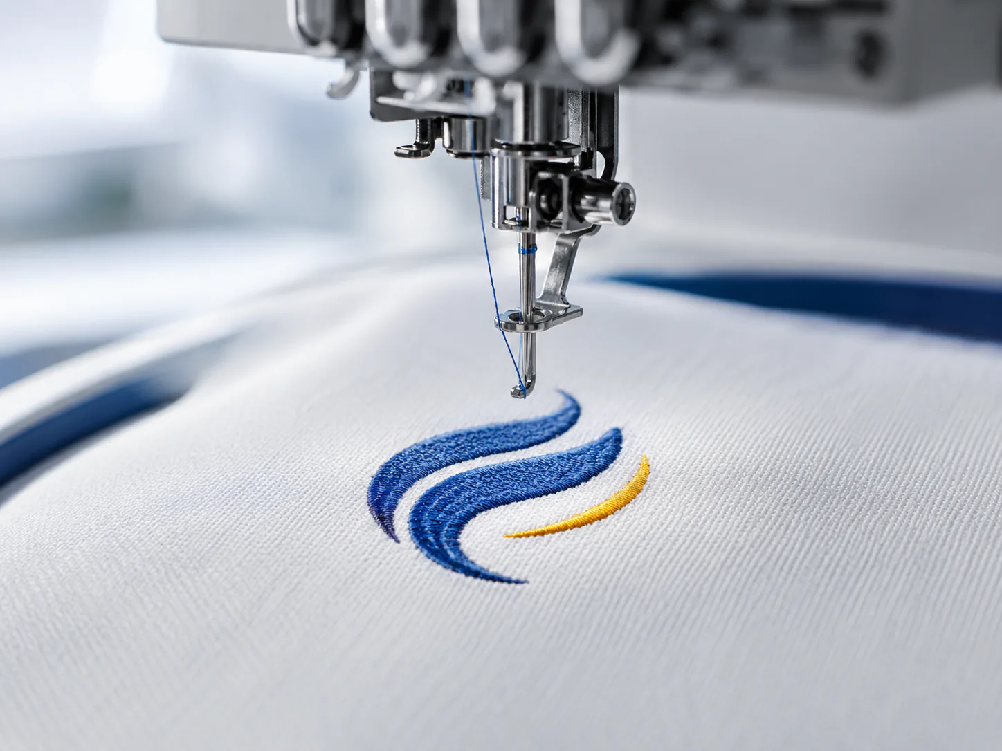 Machine réalisant une broderie personnalisée bleue et jaune sur un textile blanc